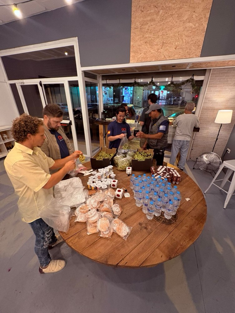 Voluntarios preparando pan, fruta y agua alrededor de una mesa de madera