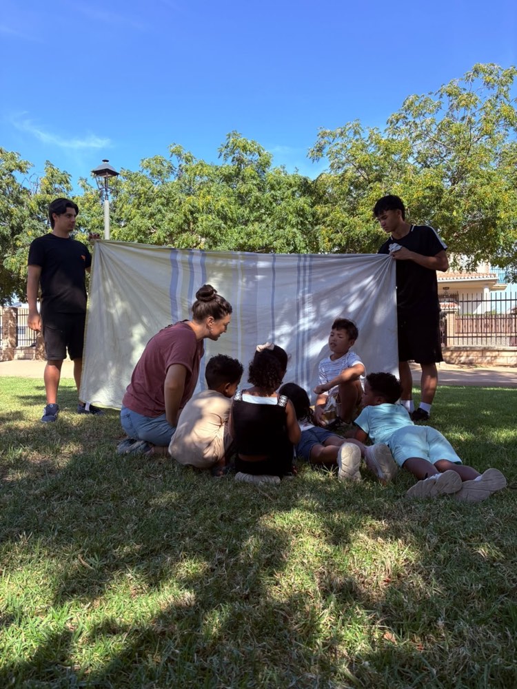Una obrera contando una historia a un grupo de niños en el césped